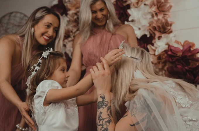 Bridal designer helping a bride and a young girl choose a wedding dress in a warm, elegant showroom.